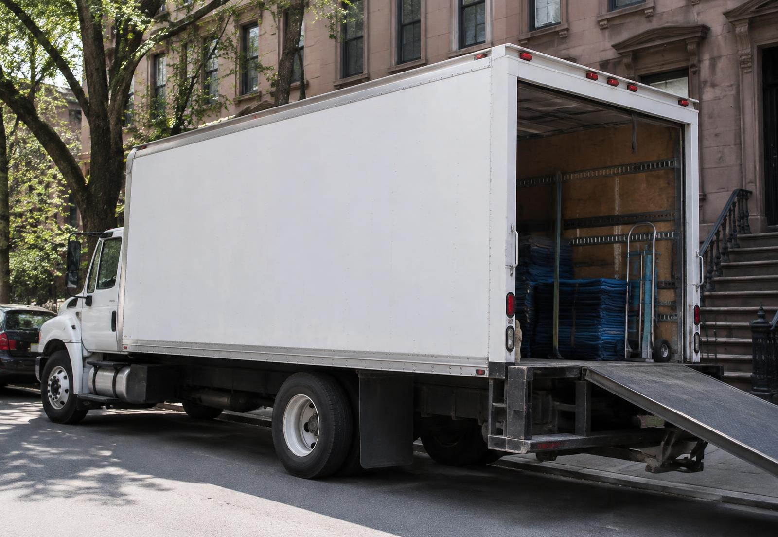 VSNY Van Lines moving truck loaded with padded furniture on a residential street